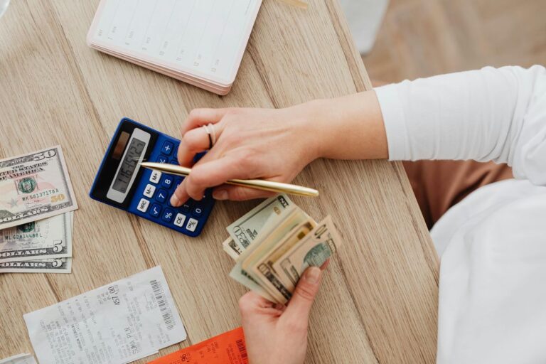 Woman counting money with calculator for budgeting